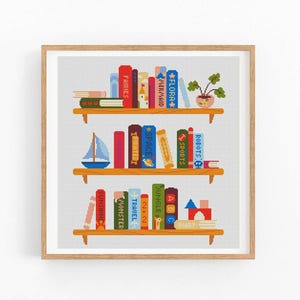 以下が含まれることがあります： 額縁に入ったクロスステッチのデザインは、3つの木製の棚がある本棚を描いています。 棚にはカラフルな本、小さなヨット、鉢植えの植物、ブロックの山が並んでいます。 本のタイトルには「Fairies」、「Mermaid」、「Robots」などがあります。