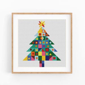 May include: A framed cross-stitch pattern featuring a stylized Christmas tree composed of various geometric shapes in vibrant colors including red, yellow, blue, green, and pink, topped with a yellow star, all set against a white grid background.