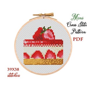 May include: A cross stitch pattern of a strawberry cake on a white background. The pattern is 39 stitches wide and 38 stitches tall. The pattern is in a wooden embroidery hoop.