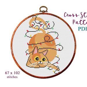 Könnte beinhalten: Kreuzstich-Muster PDF einer orangefarbenen Katze, die sich in Weihnachtslichtern verheddert hat. Das Muster ist 67 Stiche breit und 102 Stiche hoch.