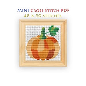May include: A mini cross stitch PDF pattern featuring a pumpkin design with orange, yellow, and brown segments, a green stem, and a green leaf. The text reads MINI CROSS STITCH PDF 48 x 50 STITCHES. The design is displayed in a light wood frame.
