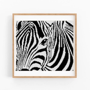 May include: A square framed wall art piece featuring a high-contrast, black and white pixelated or cross-stitch style close-up portrait of a zebra. The artwork is encased in a light-toned wooden frame, showcasing the animal's distinct striped pattern.