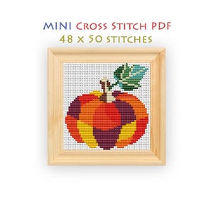 May include: A cross stitch pattern titled MINI CROSS STITCH PDF 48 x 50 STITCHES featuring a pumpkin design with segments in red, orange, yellow, and purple, topped with a green leaf, displayed inside a light-colored wooden square frame.