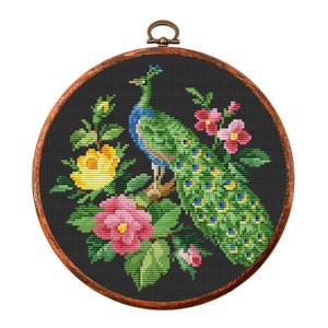 May include: A framed cross-stitch embroidery featuring a peacock with a green and blue plumage, surrounded by pink and yellow flowers on a black background.