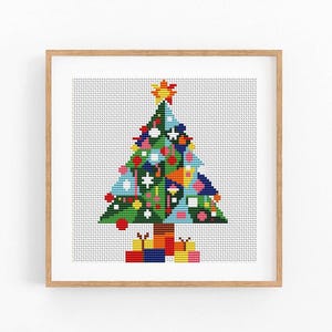 May include: A cross-stitch pattern of a Christmas tree in a light wood frame. The tree is composed of geometric shapes in green, blue, and red, decorated with colorful ornaments and a yellow star on top. Gift boxes sit at the base of the tree.
