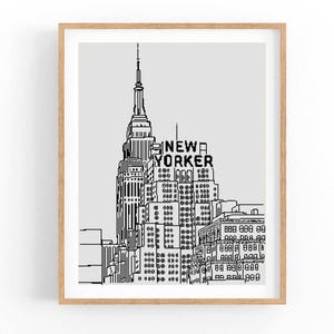 May include: A framed black and white line drawing of the New York City skyline, featuring the Empire State Building and the text "New Yorker". The artwork is set against a light gray background.
