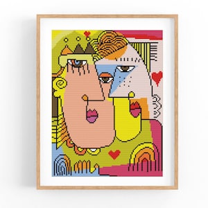 May include: Abstract art print featuring two stylized faces in a colorful, pixelated style. The artwork uses a palette of pink, yellow, blue, and red, with heart and rainbow motifs. Framed in a light wood.