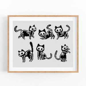 May include: A framed print featuring a cross-stitch design of seven black and white cat skeletons in various poses. The cats have detailed skeletal structures and are set against a light gray background. The frame is a light brown color.