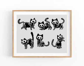 May include: A framed cross-stitch pattern featuring six pixel art cats with visible skeletal structures. The cats are rendered in black thread on a white grid background, displayed in various poses including walking, stretching, and sitting.