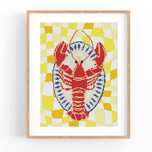 May include: A framed print featuring a red lobster design. The lobster is centered on a white plate with blue trim, set against a yellow and white checkered background. The artwork is in a cross-stitch style.