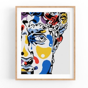 Może przedstawiać: Kolorowy abstrakcyjny portret twarzy. Twarz jest namalowana w stylu przypominającym pop art, z odważnymi kolorami i geometrycznymi kształtami. Tło jest białe.