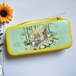 May include: A rectangular yellow pencil case with a zip closure and a carrying handle. The front panel features a light green illustration of a bamboo-style shop with small pink cartoon rabbits, bamboo stalks, and various food items.