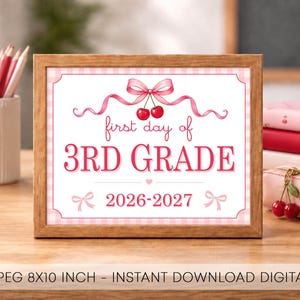 Puede incluir: Un letrero enmarcado con un borde de cuadros rosas que presenta el texto first day of 3RD GRADE 2026-2027. El diseño incluye una cinta rosa atada en un lazo con dos cerezas rojas colgando, además de dos pequeños lazos rosas en las esquinas.