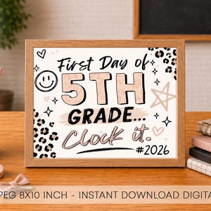 May include: A rectangular wooden frame containing a white sign with the text First Day of 5TH GRADE... Clock it. #2026. The design features black and tan leopard print patterns, a smiley face, stars, and hearts in a neutral color palette.