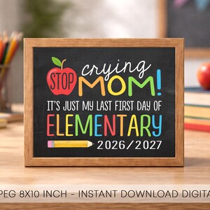 May include: A rectangular chalkboard sign with a wooden frame featuring the text STOP CRYING MOM! IT'S JUST MY LAST FIRST DAY OF ELEMENTARY 2026/2027. The design includes a red apple graphic and a yellow pencil graphic in colorful lettering.