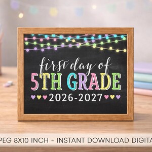 Könnte beinhalten: Ein rechteckiger Holzrahmen mit einem Schild im Tafel-Stil und dem Text "first day of 5TH GRADE 2026-2027". Das Design zeigt bunte Lichterketten am oberen Rand und kleine Herzen neben der Jahreszahl, alles vor einem schwarzen Hintergrund.