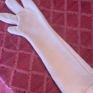 Puede incluir: Un guante largo de color rosa de forro polar con tres dedos y un pulgar.