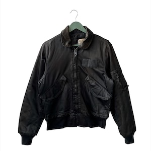 May include: A black bomber jacket with a zip fastening and multiple pockets. The jacket has a ribbed collar and cuffs.