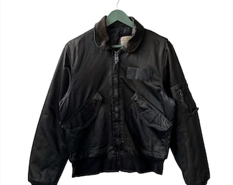 May include: A black bomber jacket with a zipper closure and multiple pockets. The jacket has a ribbed collar and cuffs.