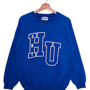 May include: A royal blue sweatshirt with a white "HU" logo in a collegiate style font. The letters "SRT" are printed vertically to the left of the "H".