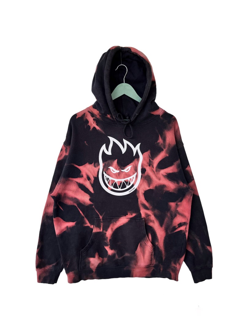 May include: Black and red tie-dye hoodie with a white "Spitfire" logo featuring a flame with a face.