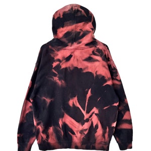May include: A red and black tie-dye hoodie with a drawstring hood.