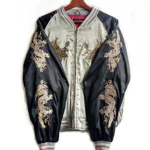 May include: A black and light green satin bomber jacket with gold embroidered dragons on the sleeves and eagles on the front. The jacket has a zipper closure and ribbed cuffs and collar.