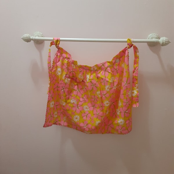 1960s mod floral apron, retro ladies' pink yellow white daisy half-apron with rick rack trim and pocket