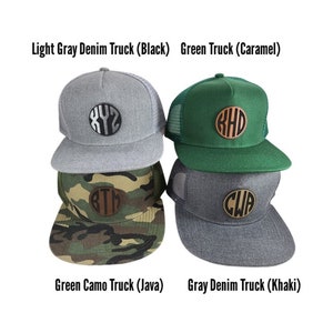 May include: Four trucker hats with different colored fabrics and embroidered leather patches. The hats are stacked on top of each other. The patches have the letters "XYZ", "KHD", "BTM", and "CWA" on them. The hats are labeled "Light Gray Denim Truck (Black)", "Green Truck (Caramel)", "Green Camo Truck (Java)", and "Gray Denim Truck (Khaki)".