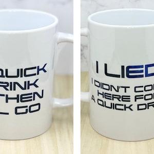 May include: White ceramic mug with a black and blue design. The text on the mug reads "A quick drink & then I'll go" on one side and "I lied I didn't come here for a quick drink" on the other side.