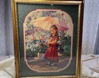 May include: A framed print of a young girl holding a pink umbrella in a garden setting. The girl is wearing a red dress and is surrounded by flowers. The print is in a gold frame with a green mat.