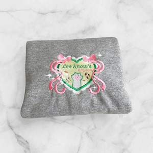 May include: Gray sweatshirt with a pink and green embroidered design of a heart with the text "Lee Know's Kitty Cafe" inside.