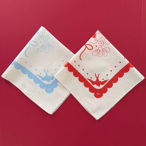 Puede incluir: Dos pa&ntilde;uelos blancos con un dise&ntilde;o floral y de p&aacute;jaros. Uno tiene un borde festoneado y detalles azules, el otro un borde festoneado y detalles rojos. Cada pa&ntilde;uelo tiene la palabra "Sam" impresa.