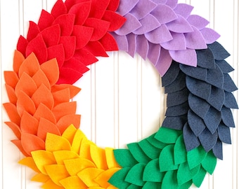 May include: A colorful felt wreath with red, orange, yellow, green, blue, and purple leaves. The wreath is made of felt and is perfect for a spring or summer decoration.