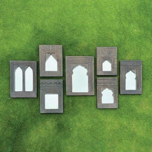 May include: Eight decorative wooden framed mirrors with arched tops, arranged in a row on a green grassy surface.
