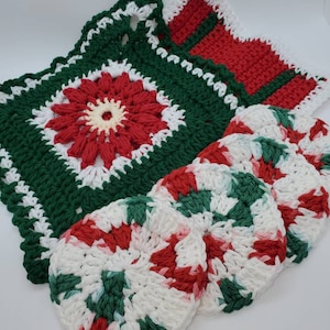 May include: Set of five crocheted dishcloths in red, green, and white. The dishcloths are in the shape of candy canes and a flower.