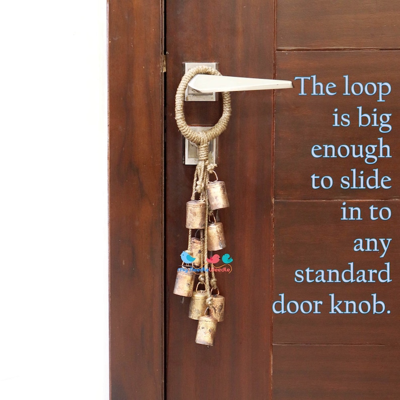 May include: A brown wooden door with a silver door knob and a rope loop with a string of gold bells hanging from it. The text "The loop is big enough to slide in to any standard door knob." is written in blue text on the right side of the door.