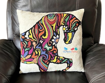 May include: A white pillow with a colorful embroidered design of a horse. The horse is outlined in black and filled with bright colors like red, yellow, blue, green, and purple. The pillow has the text "my needle doodle" embroidered in the bottom right corner.