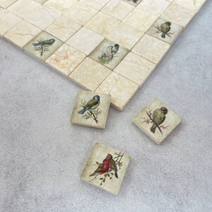 May include: Four square ceramic tiles with images of birds on branches. The tiles are beige with a light brown veining. The birds are a bluebird, a sparrow, a robin, and a sparrow.