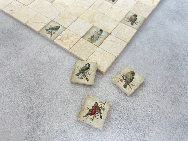 May include: Four square ceramic tiles with images of birds on branches. The tiles are beige with a light brown veining. The birds are a bluebird, a sparrow, a robin, and a sparrow.