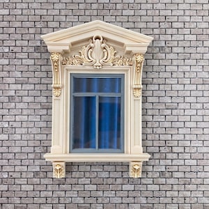 Può includere: Una cornice decorativa per finestre con dettagli dorati ornati e una tenda blu. La finestra è posta contro un muro di mattoni. La cornice ha un frontone e intagli decorativi.