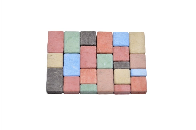 May include: A collection of small, square, concrete pavers in various colors, including red, green, blue, and gray. The pavers are arranged in a grid pattern.