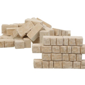 Peut inclure: Un tas de blocs de pierre beige, dont certains sont empilés pour former un petit mur. Les blocs ont une surface rugueuse et texturée.