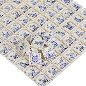 Puede incluir: Una hoja de azulejos de cerámica blanca con diseños de gatos azules y blancos. Los azulejos están dispuestos en una cuadrícula y son perfectos para un salpicadero de cocina o una pared de baño.
