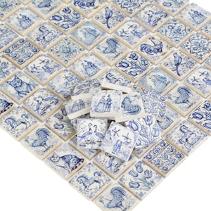 Puede incluir: Una colección de azulejos de cerámica azul y blanco con varios diseños de inspiración holandesa, incluyendo molinos de viento, tulipanes, gatos y gallos.