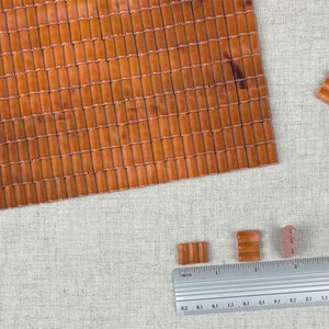 May include: A sheet of brown bamboo tiles with a ruler and several smaller tiles in the foreground. The ruler is marked in inches.