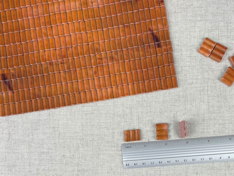 May include: A sheet of brown bamboo tiles with a ruler and several smaller tiles in the foreground. The ruler is marked in inches.