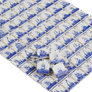 May include: A collection of small, square ceramic tiles with a nautical theme. Each tile features a blue and white illustration of a sailboat on the sea. The tiles are arranged in a grid pattern, creating a decorative surface.