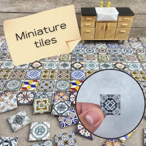 May include: A collection of miniature ceramic tiles featuring intricate patterns in shades of blue, yellow, red, and white. The tiles are arranged in a mosaic pattern, creating a visually appealing design. The text "miniature tiles" is written on a notecard in the top left corner of the image.
