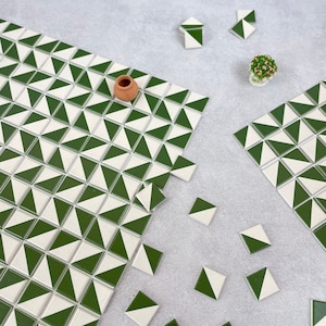 May include: Green and white geometric tile pattern. The tiles are arranged in a staggered pattern to create a chevron design. The tiles are made of ceramic and have a glossy finish.